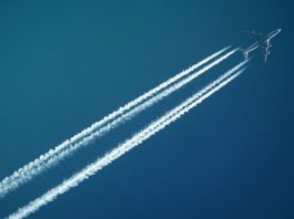 white airplane with smoke under blue sky